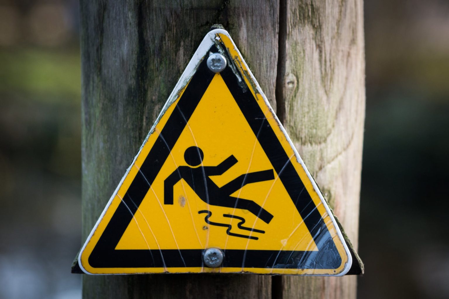 Worn slip and fall warning sign attached to a post