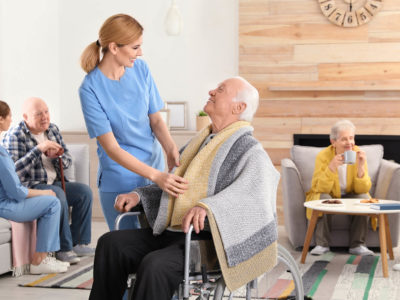 Elderly man in wheelchair accompanied by a nurse
