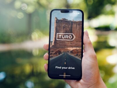 Hand Holding A Smartphone With Turo Online