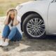 Woman sitting beside a car after an accident.